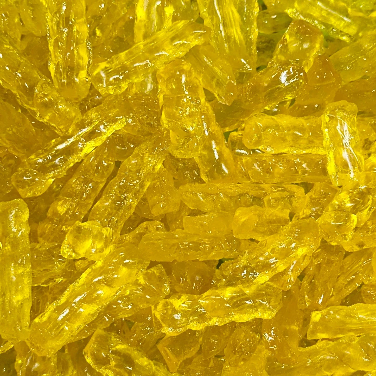 “Close-up of golden yellow barley sugar twist candies with a glossy, translucent surface, showing their classic twisted shape