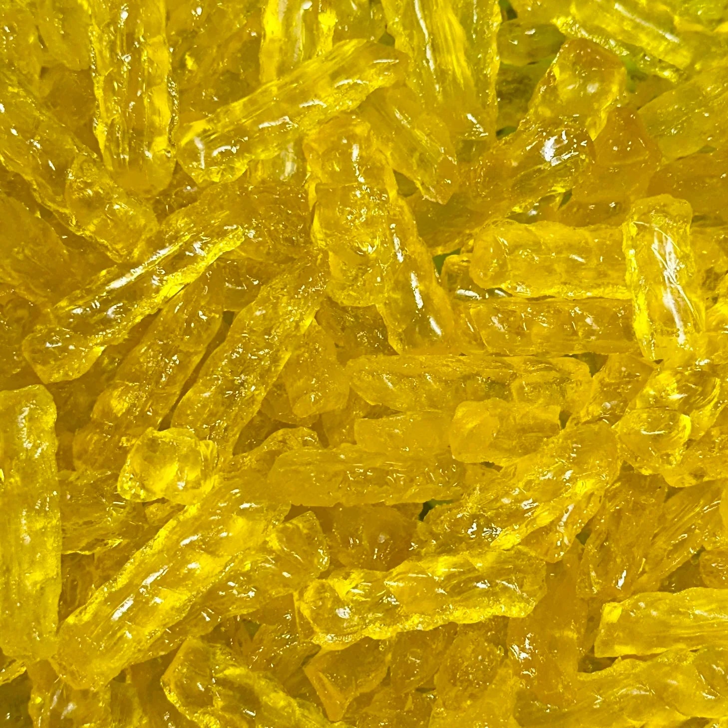 “Close-up of golden yellow barley sugar twist candies with a glossy, translucent surface, showing their classic twisted shape
