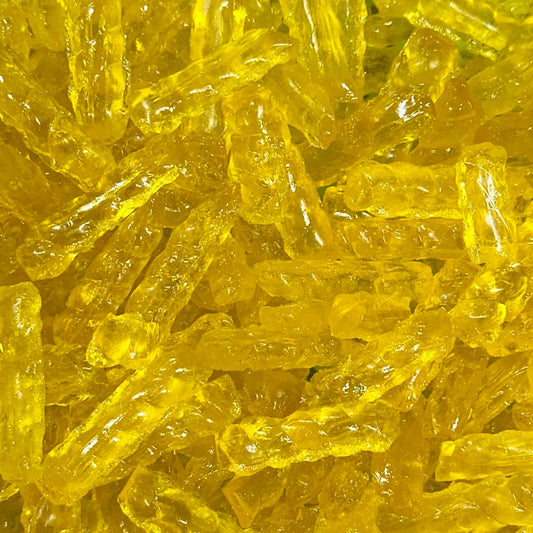 “Close-up of golden yellow barley sugar twist candies with a glossy, translucent surface, showing their classic twisted shape