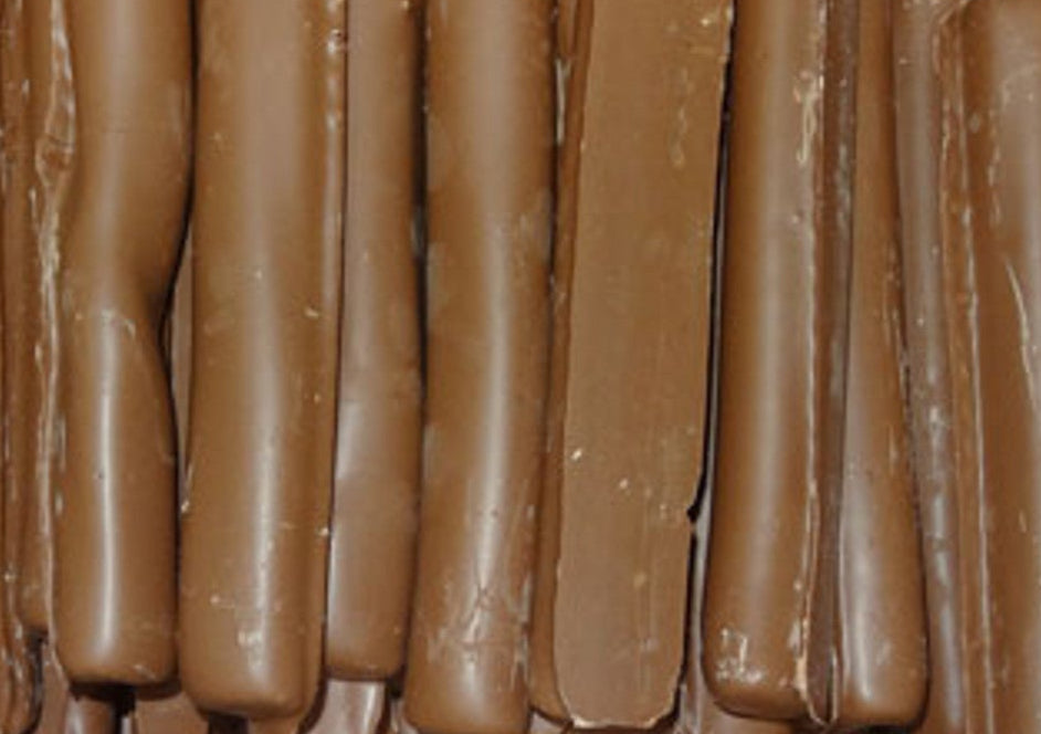 Close-up of rich chocolate-coated licorice logs from Lolliland, glossy milk chocolate exterior with soft black licorice center, neatly arranged for display.