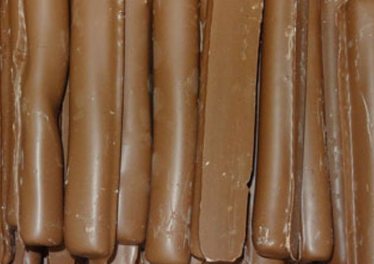 Close-up of rich chocolate-coated licorice logs from Lolliland, glossy milk chocolate exterior with soft black licorice center, neatly arranged for display.
