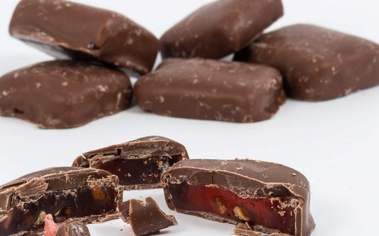 “Close-up of milk chocolate-coated Turkish delight pieces, showing the glossy chocolate exterior and soft rose-flavoured jelly centre, displayed on a white background.”