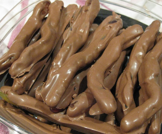 “Close-up of chocolate-coated gummy snakes stacked together, showing their glossy milk chocolate coating and chewy candy texture on a white background.”