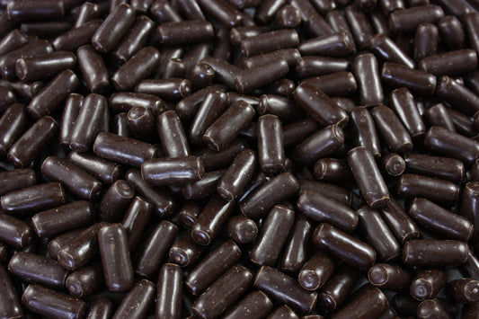“Close-up of dark chocolate-coated licorice bullets with a glossy finish, displayed on a white background for a professional confectionery product image.”