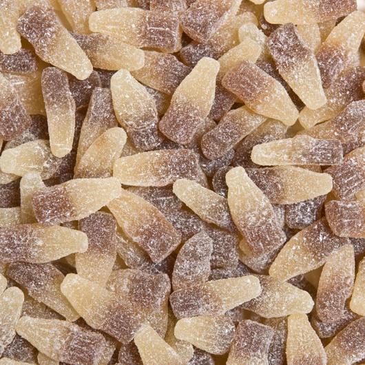 Sour cola bottle-shaped lollies coated in sugar, displayed on a white background showing their fizzy texture and brown-and-clear colour.