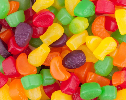 “Close-up of assorted colourful fruit-shaped gummy candies in red, yellow, orange, and green hues.”