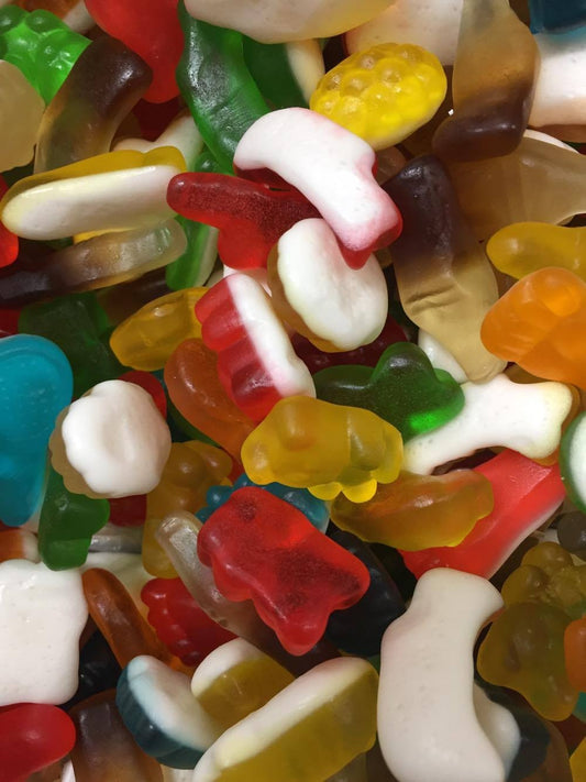 “Close-up of colourful gummy candy party mix including bears, snakes, rings, and cola bottles, arranged together on a bright surface.”