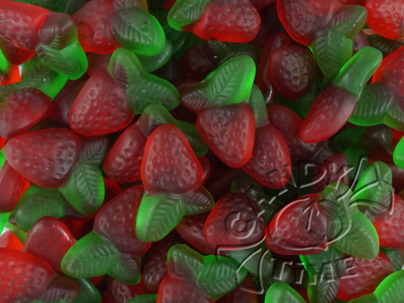 “Close-up of red and green strawberry-shaped gummies with sugar coating, designed to resemble strawberries with leaves, on a white background.”