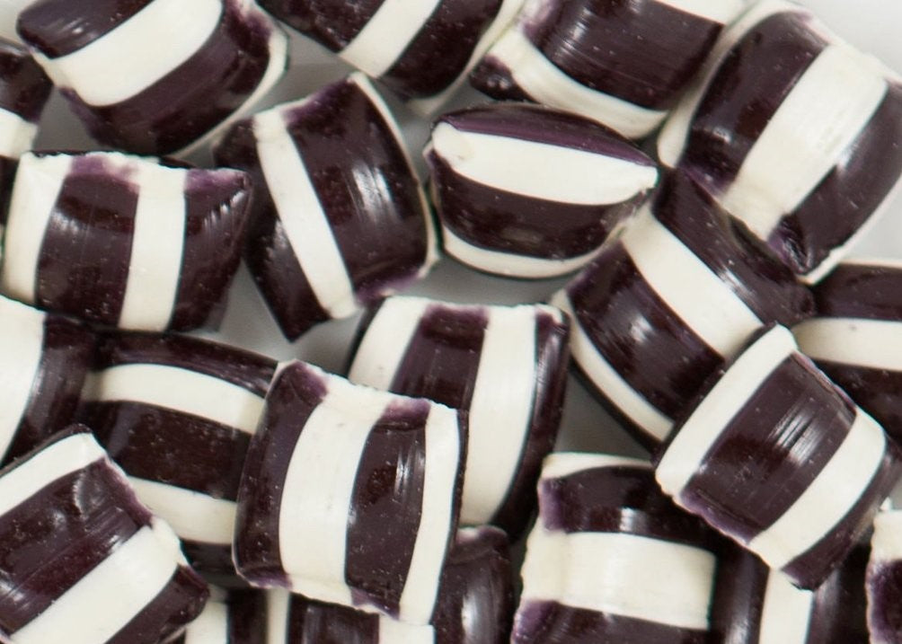 “Close-up of traditional black and white striped humbug candies with a glossy finish, arranged in a small pile on a clean white background.”