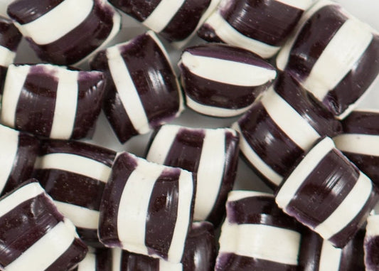 “Close-up of traditional black and white striped humbug candies with a glossy finish, arranged in a small pile on a clean white background.”