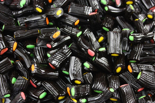 “Close-up of colourful licorice fruit bites in assorted fruity flavours, showing soft chewy texture with a glossy finish on a white background.”