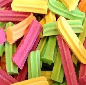 Colourful mini fruit-flavoured chewy sticks in red, yellow, orange and green, arranged on a white background.