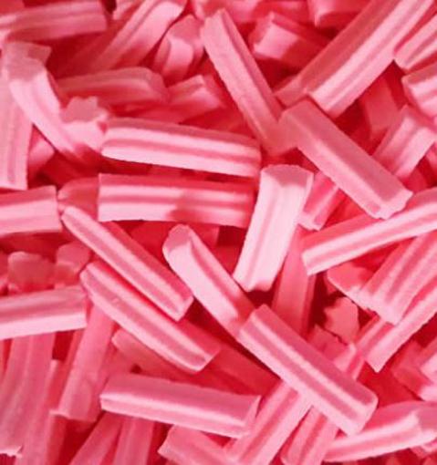 Pink mini musk stick lollies piled together on a white background, showing their smooth, pastel pink texture and cylindrical shape.