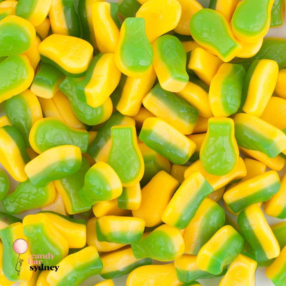 “Close-up image of pineapple-shaped gummy lollies in bright yellow and green colours, arranged together on a clean surface.”