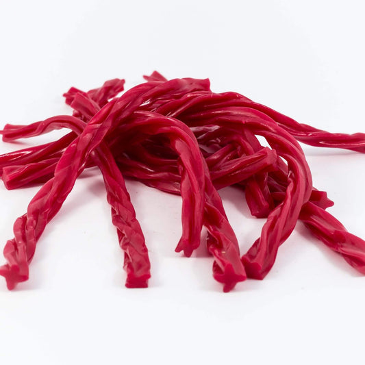 Bright red raspberry-flavoured licorice twists piled together on a white background, showing their chewy texture and twisted shape.