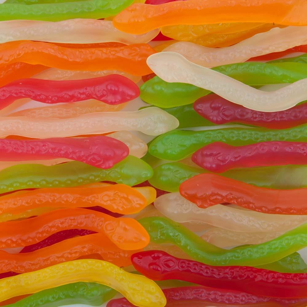Colourful gummy snakes in red, green, orange, and yellow, displayed on a white background showing their soft and chewy texture.