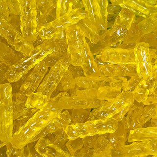 “Close-up of golden yellow barley sugar twist candies with a glossy, translucent surface, showing their classic twisted shape 