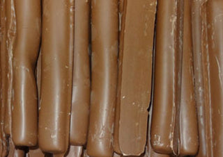 Close-up of rich chocolate-coated licorice logs from Lolliland, glossy milk chocolate exterior with soft black licorice center, neatly arranged for display.