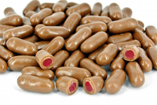 “Close-up of chocolate raspberry bullets — chewy raspberry centres coated in smooth milk chocolate, displayed on a clean white background.”
