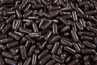 “Close-up of dark chocolate-coated licorice bullets with a glossy finish, displayed on a white background for a professional confectionery product image.”