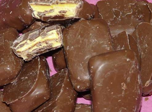 “Close-up of chocolate-coated pineapple lumps with a bright yellow pineapple-flavoured centre, arranged in a pile on a clean white background.”
