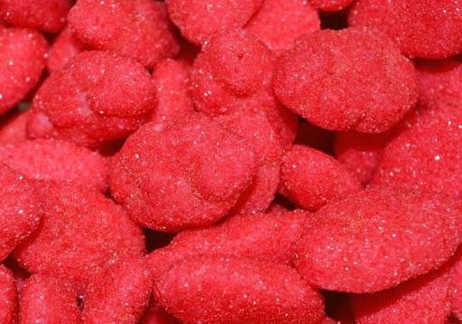 Soft red and white strawberry-shaped cloud lollies coated in sugar, displayed on a white background showing their fluffy, chewy texture.